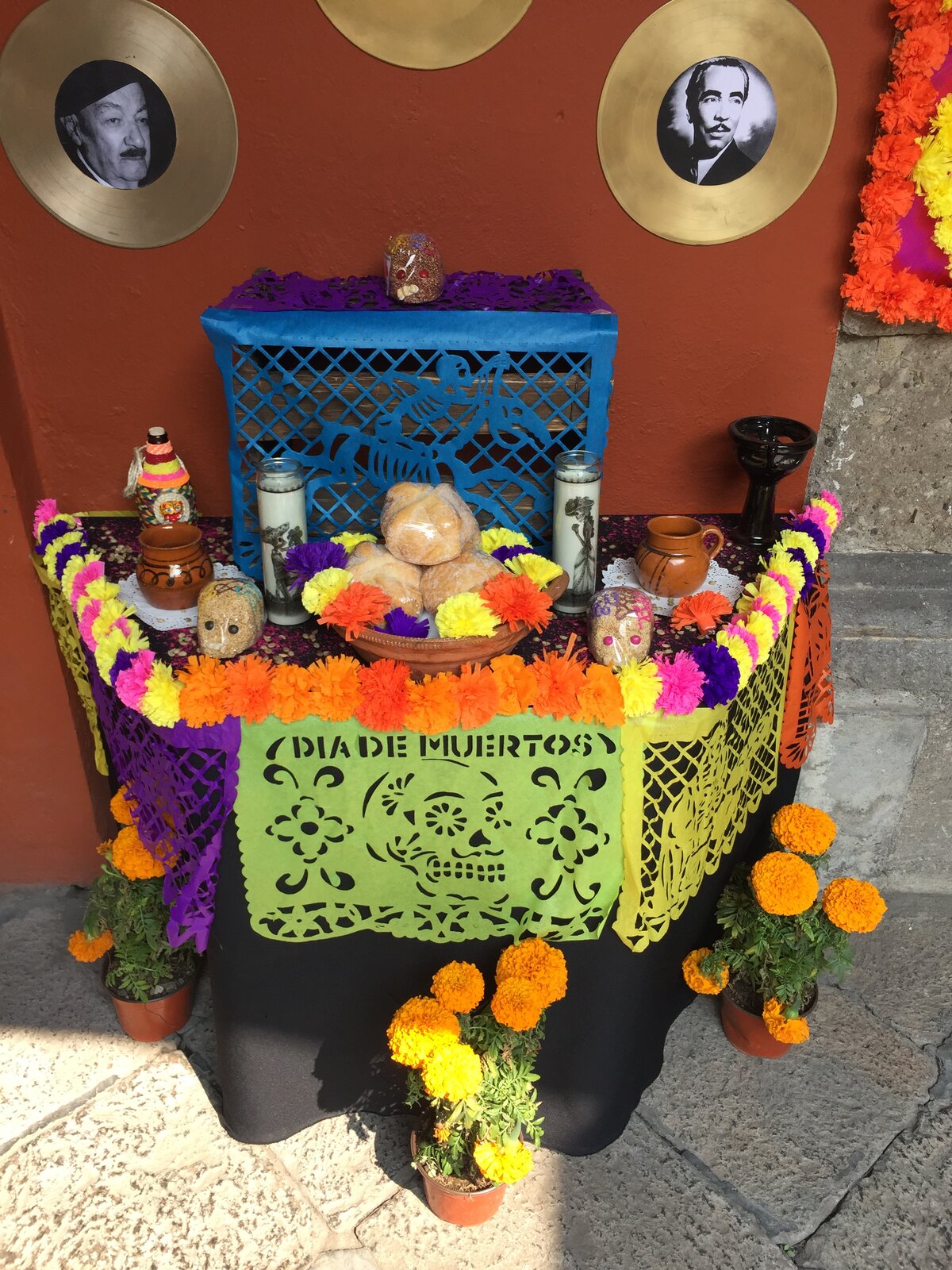 Ofrenda tradicional de Día de Muertos con flores, velas, pan y papel picado